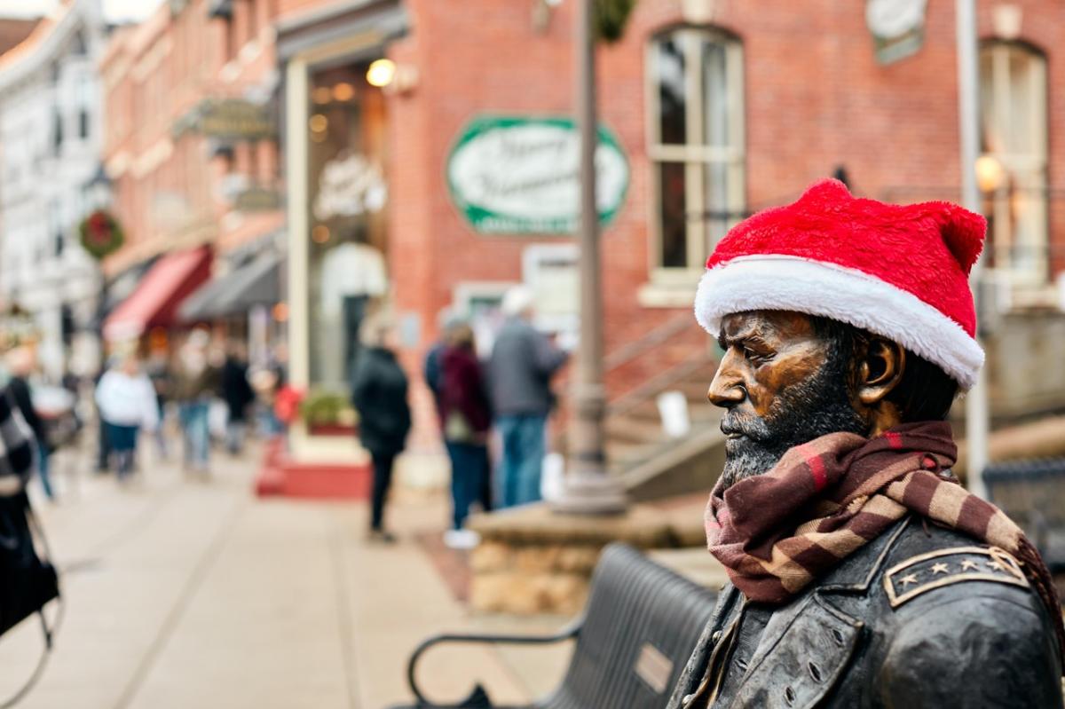 Statue of Ulysses S. Grant with a Santa hat on its head, with the red brick buildings in the background.