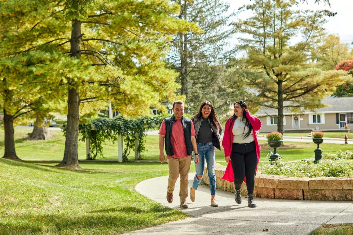 Three people walking a path through a park.