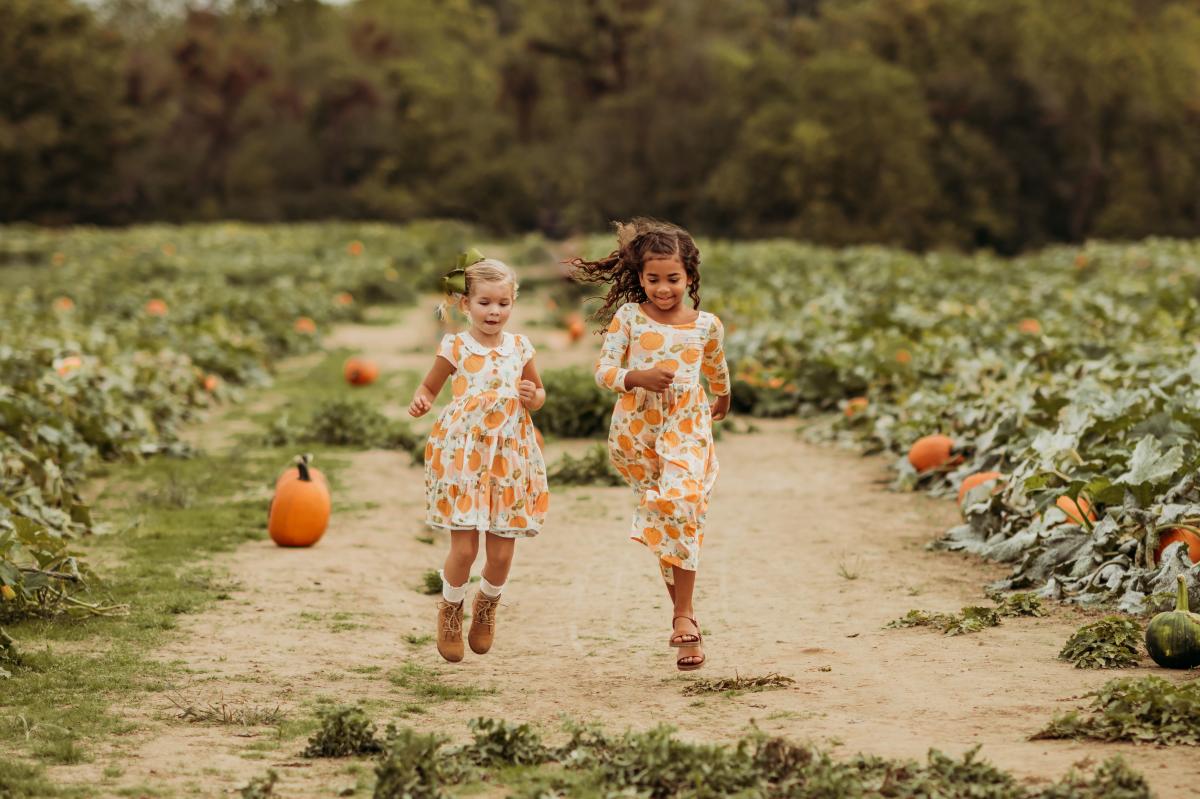 Two girls skipping through a pumpkin patch