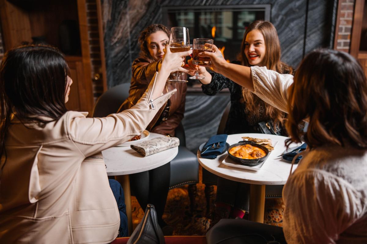 Women seated at tables, toasting