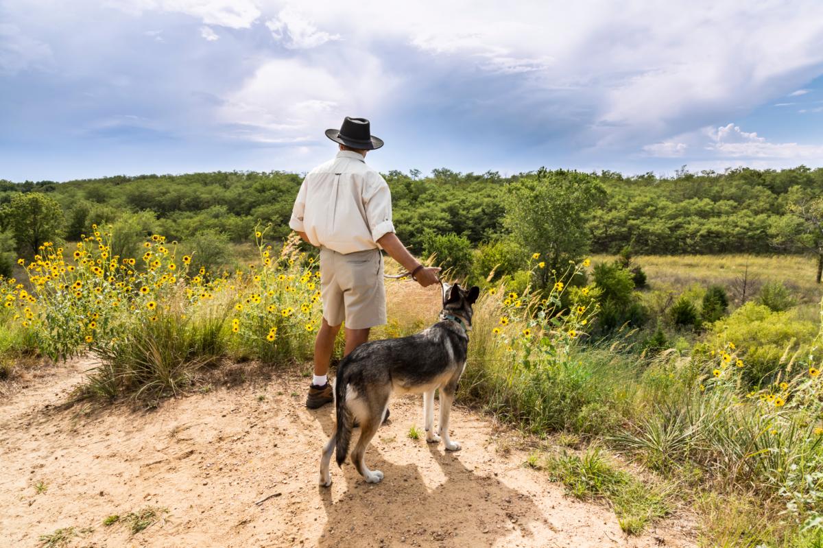 A man hiking with his dog through Sand Hills