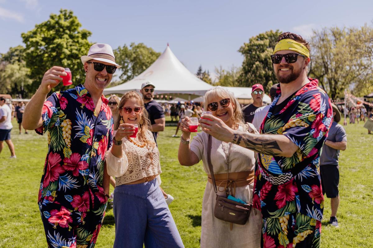 Four people stand together holding beer tasing glasses at Kelowna Beer Fest