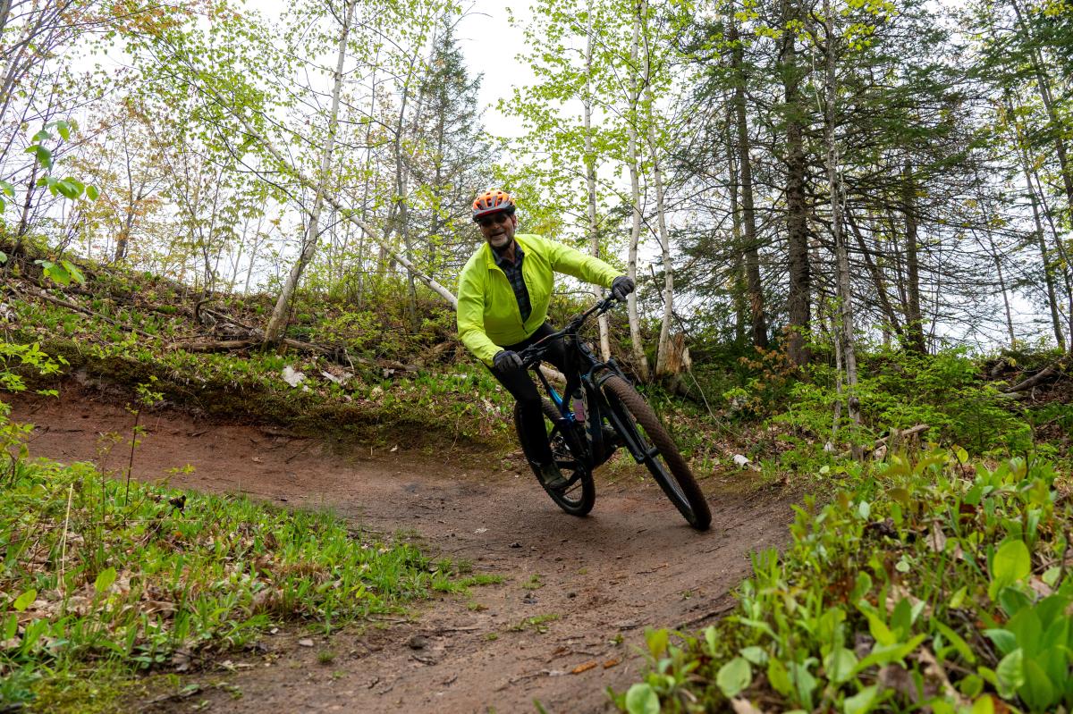 Biker bikes down wooded hilly mountain bike trail