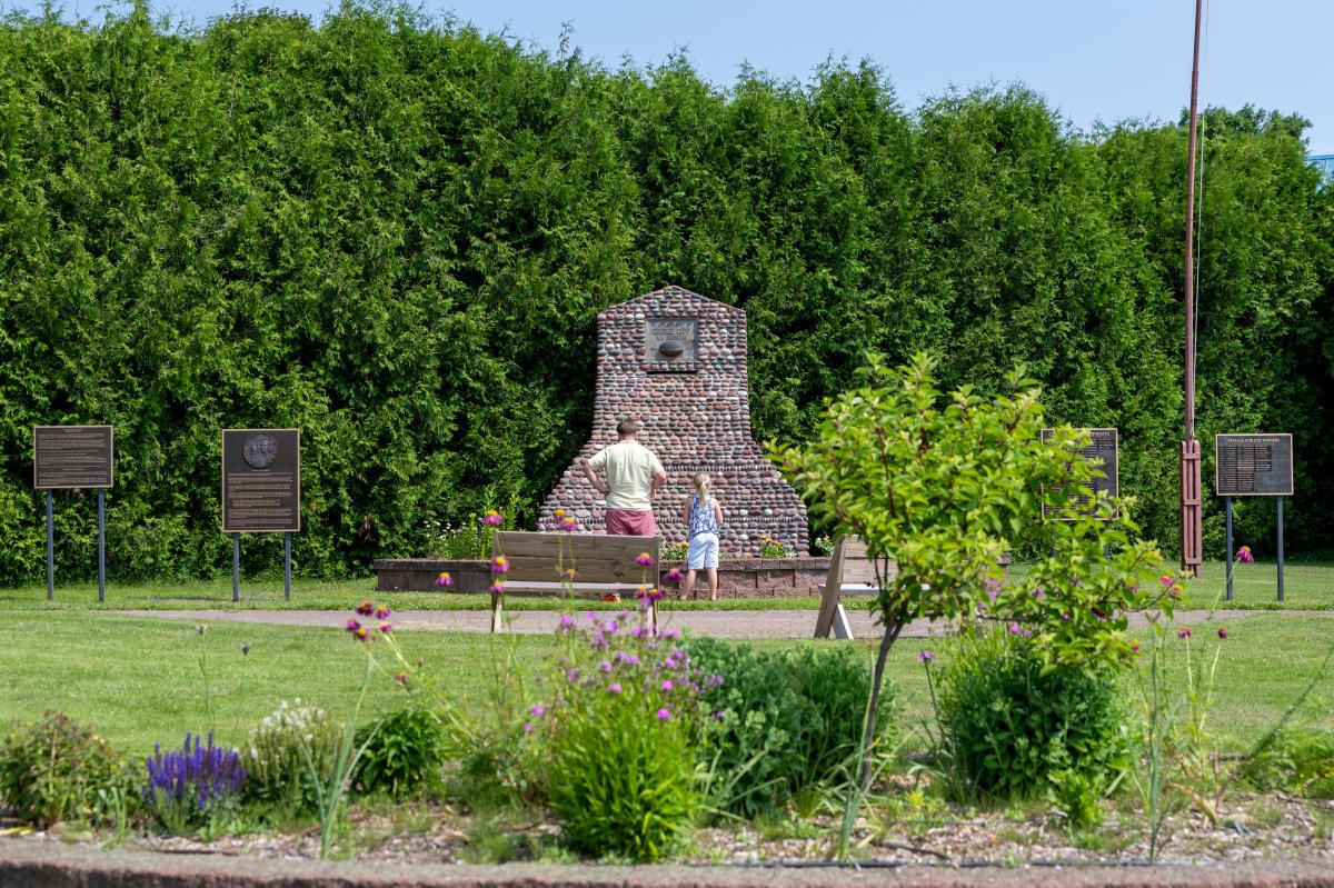 an adult and child stand in front of a stone memorial