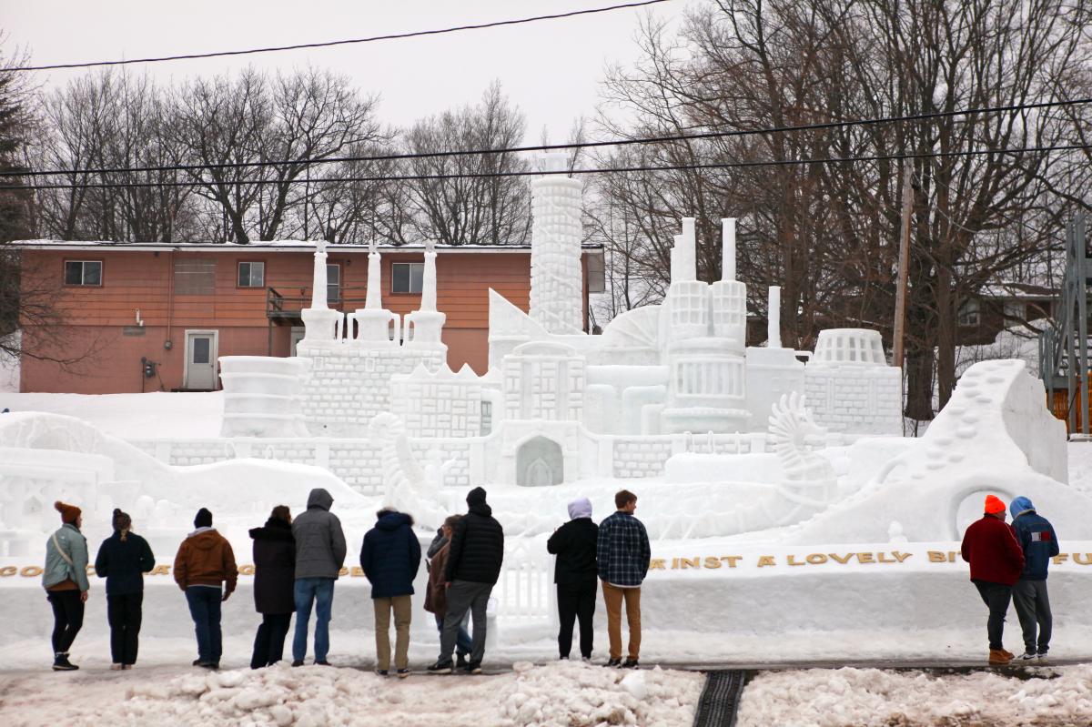 Public looks at the winning snow sculpture from winter carnival 2023.
