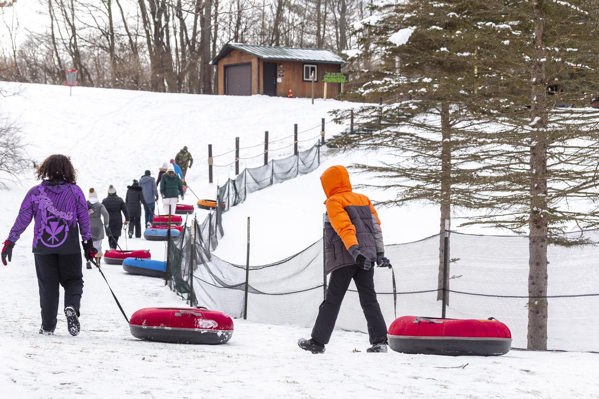 People pulling tubes up a snow hill