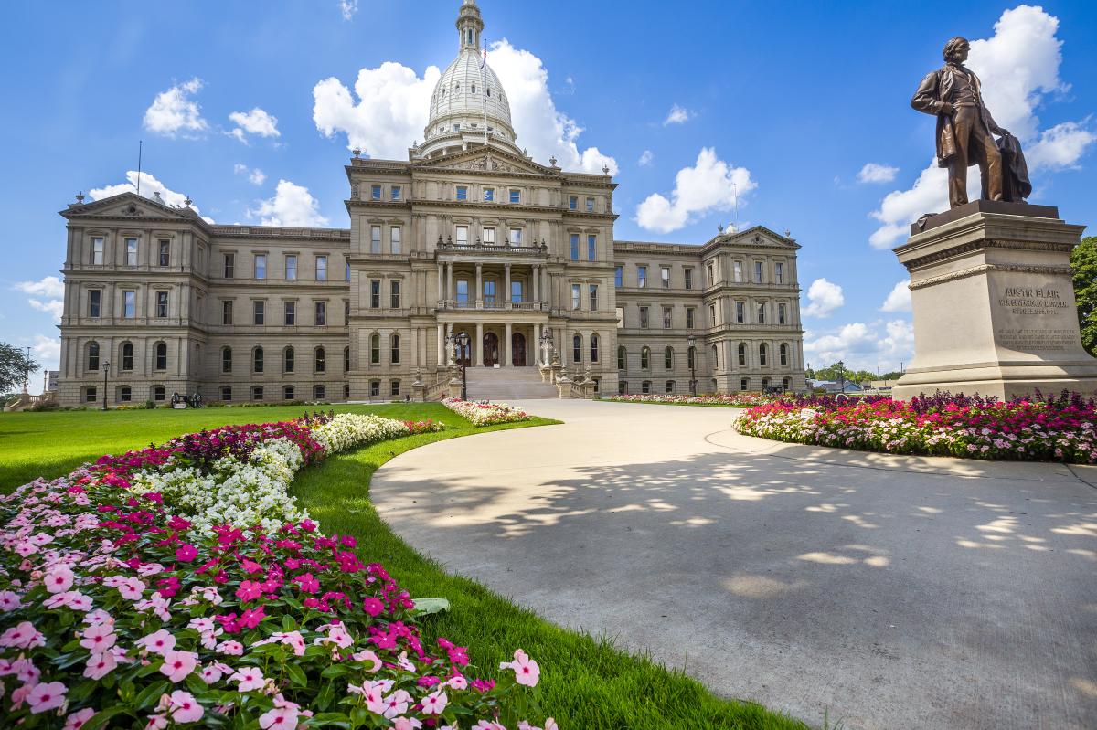 Michigan's State Capitol Building with pink and white flowers planted in front of it