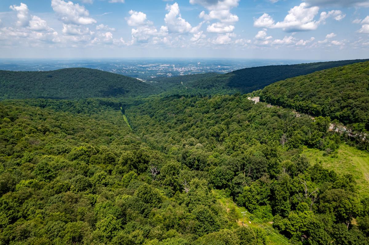 a section of the National Road Heritage Corridor with a winding road, mountains, and trees with the city of Uniontown in the distance.