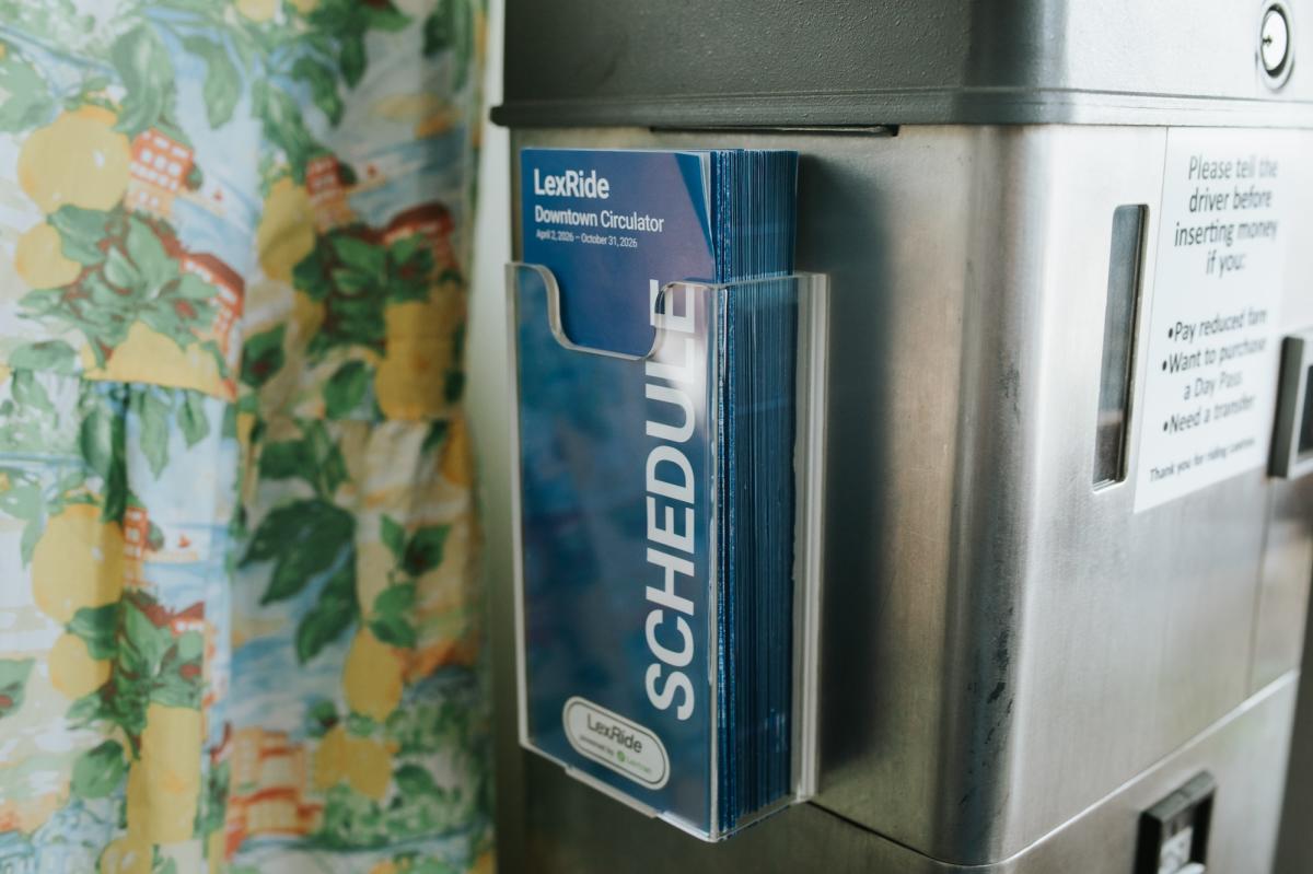 Close-up of a LexRide printed bus schedule and route map attached to a metal transit pole or bus stop.