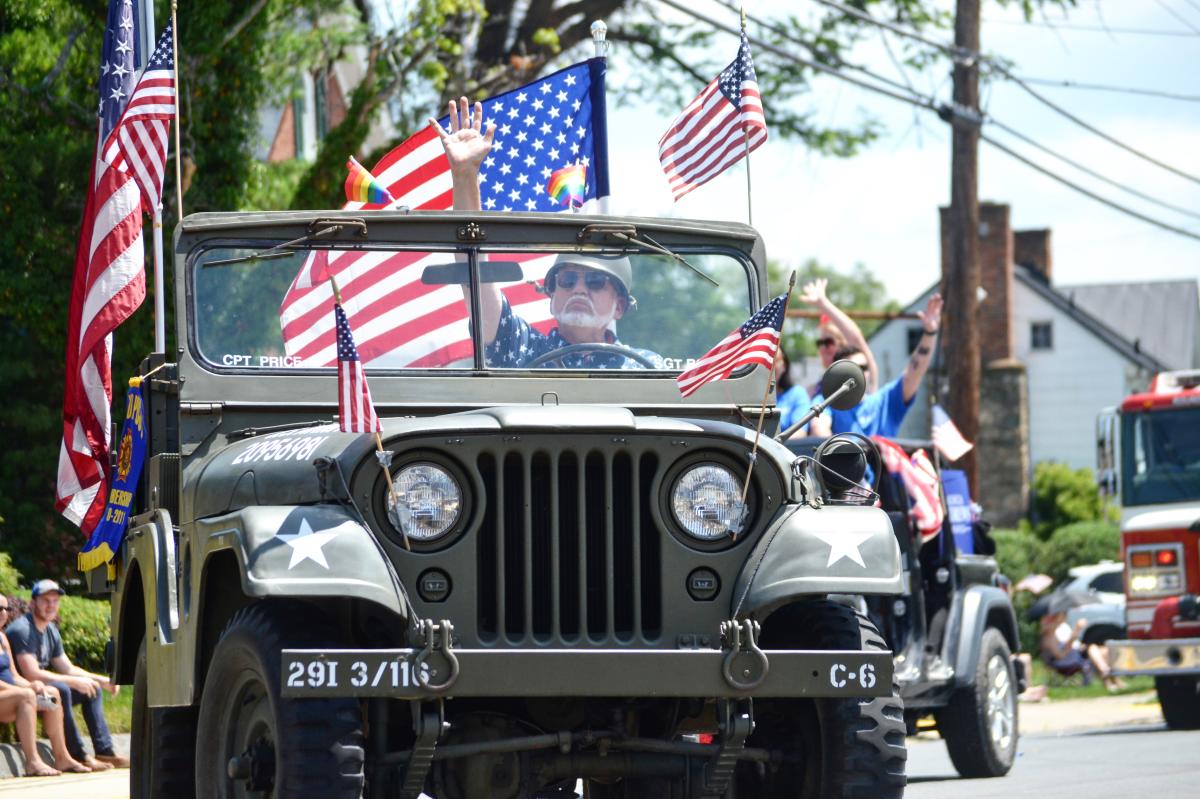 A man drives an Army Jeep with small American flags mounted on the hood during the Purcellville 4th of July