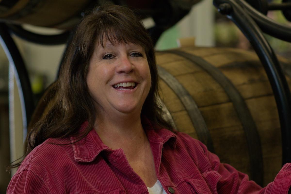 Lori Corcoran of Corcoran Vineyards & Cider beside aging barrels in Waterford, Loudoun County