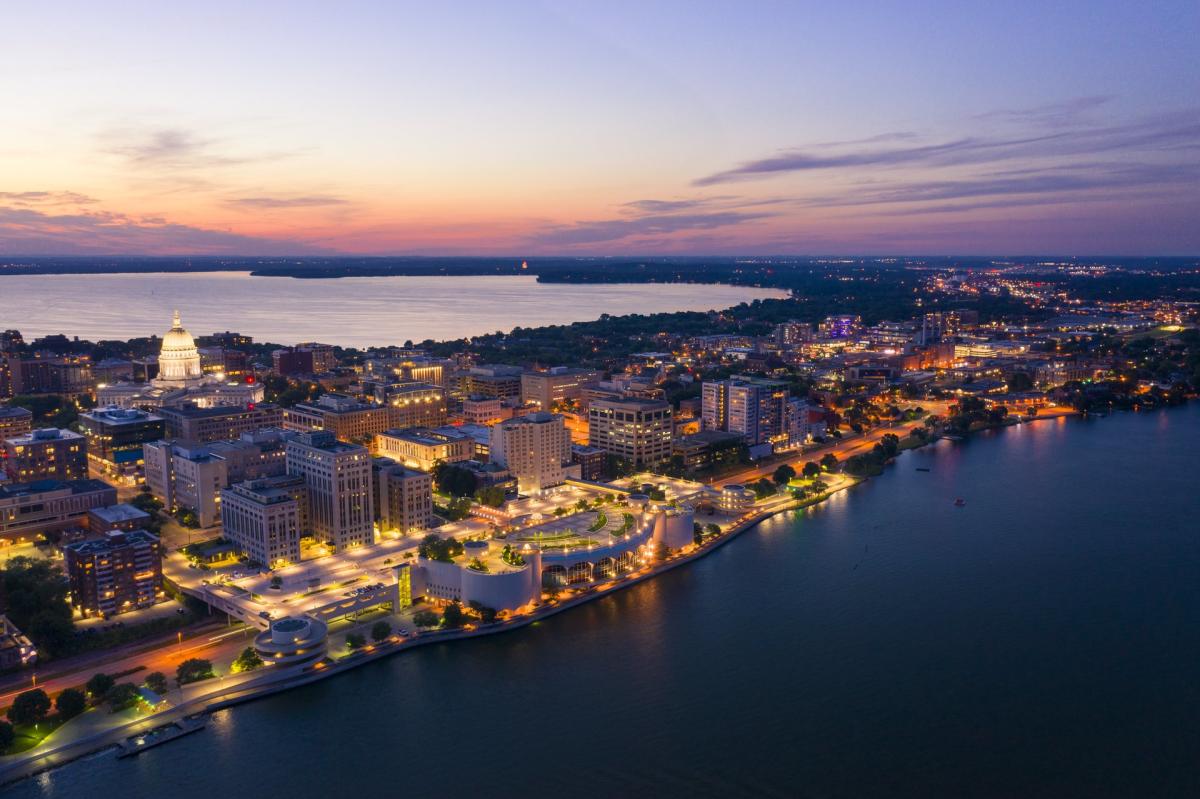 An aerial view of Downtown Madison and the isthmus lit up as dusk approaches