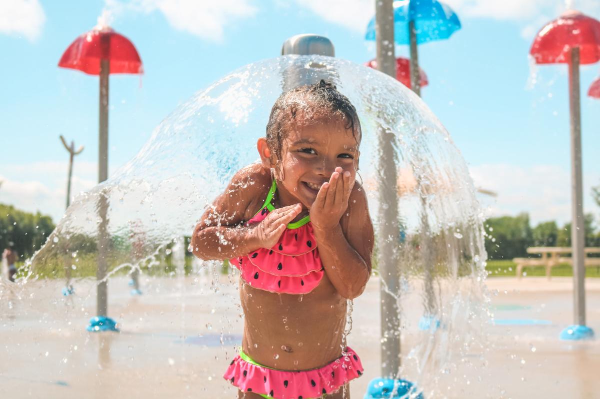 A child poses at the splash pad