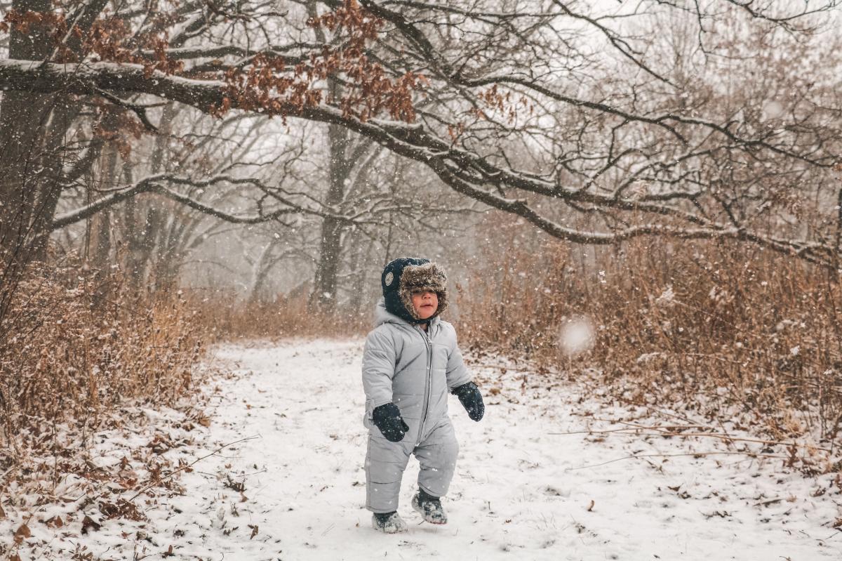 A toddler hikes in a snowsuit