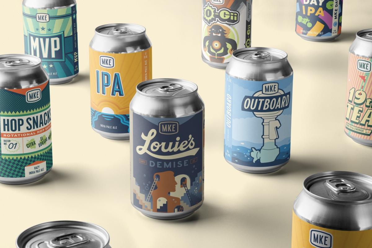 A grouping of various beer cans spread across a cream table with their labels facing out at you.