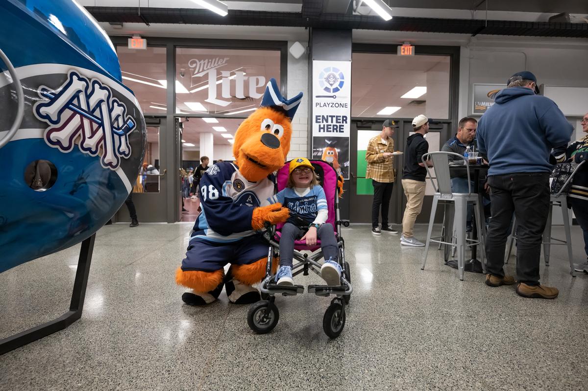 The Milwaukee Admirals mascot, Roscoe, with a young fan in a wheelchair.