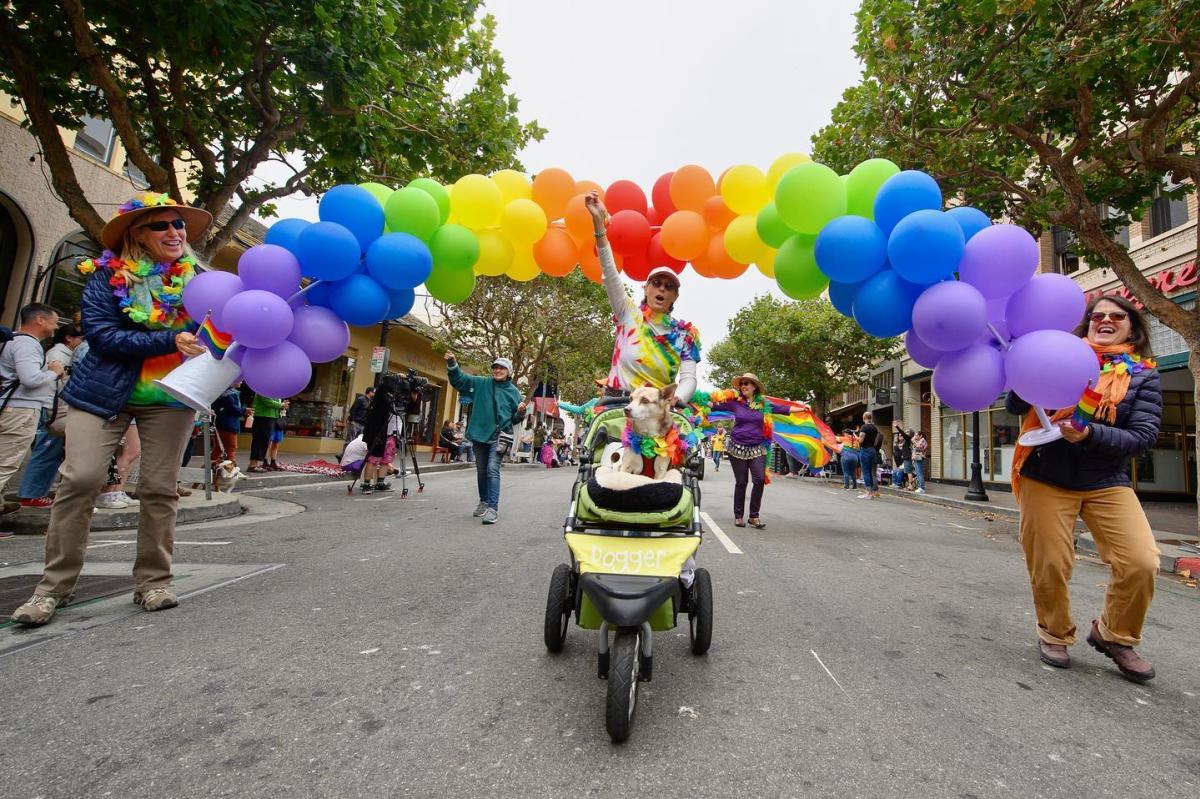 People holding a rainbow made of balloons at the Monterey Peninsula Pride