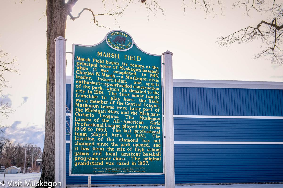 Green Historical Marker for Marsh Field stands in front of blue wall
