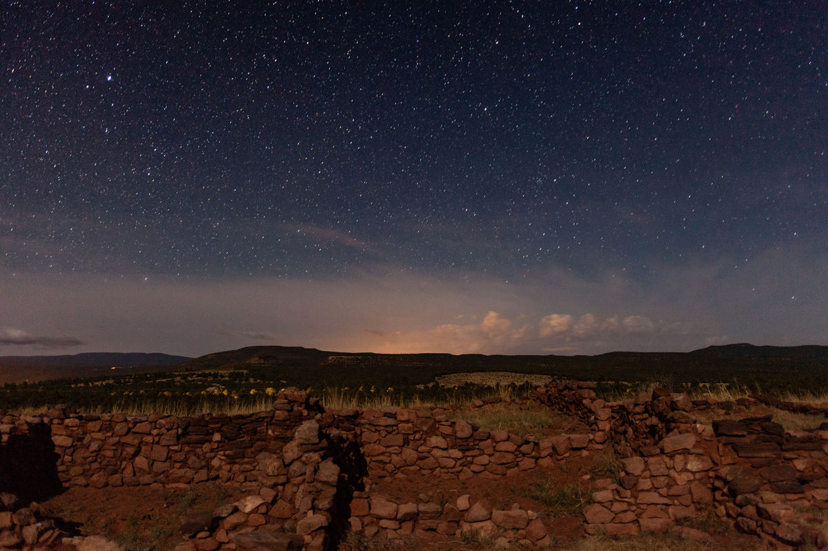 Deteriorating stone walls sit beneath a starry sky with clouds far on the horizon