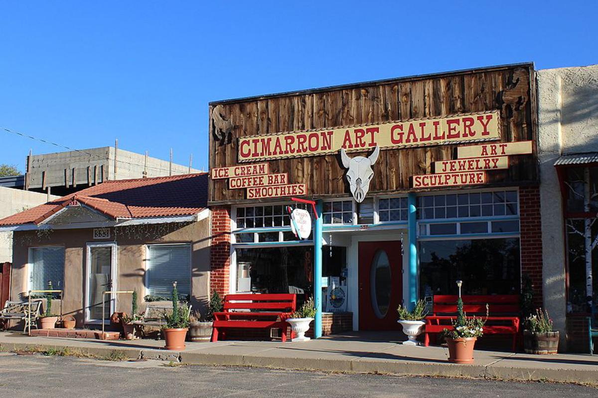 A rustic wooden store from next to an adobe store front, with a sign reading "Cimarron Art Gallery"