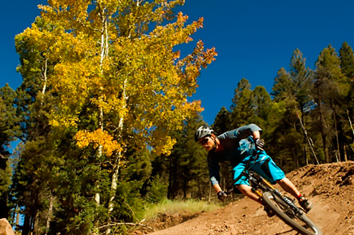 A mountain biker rides down the hill as the leaves change color on the Enchanted Circle Scenic Byway in New Mexico