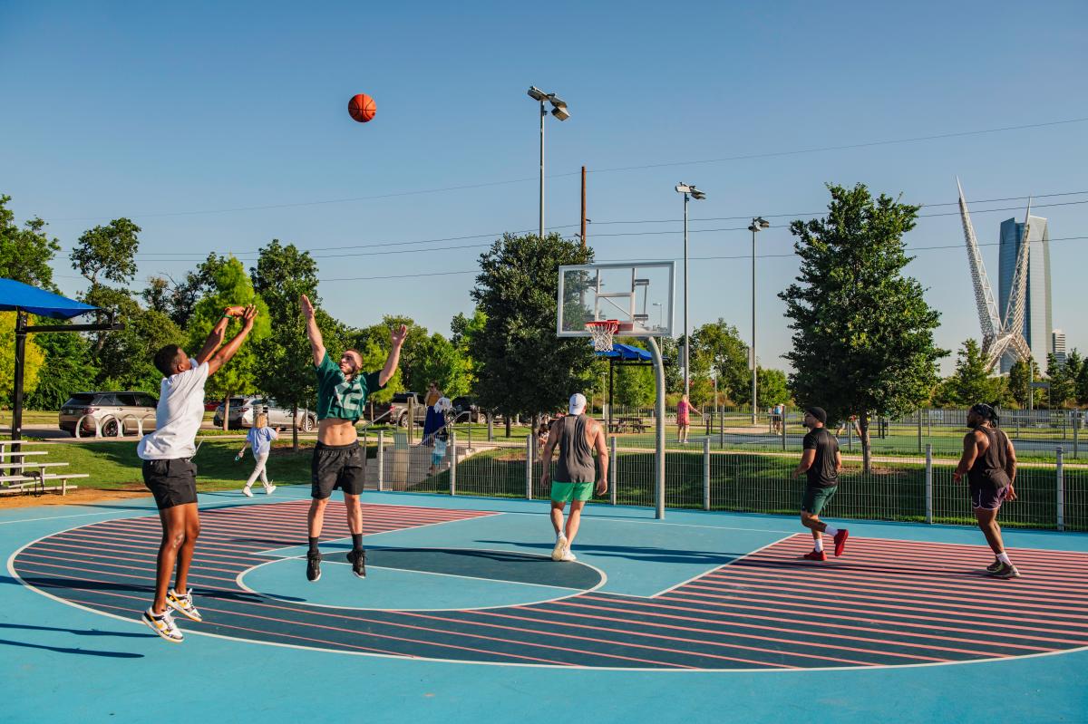 Group of people playing basketball in Lower Scissortail Park