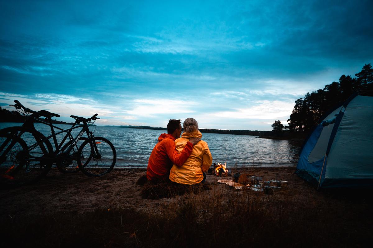 Mann og kvinne på sykkel- og campingtur ved stranda