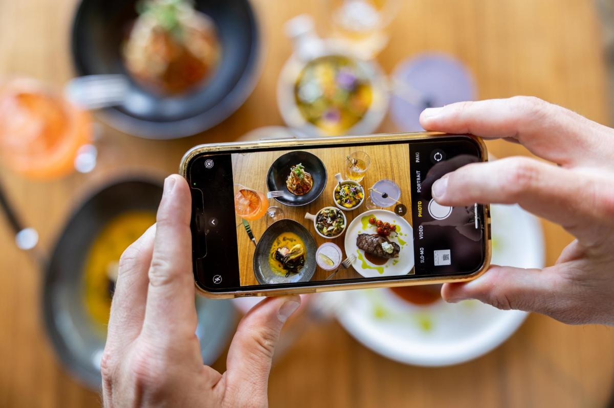 Hand taking a photo of food.