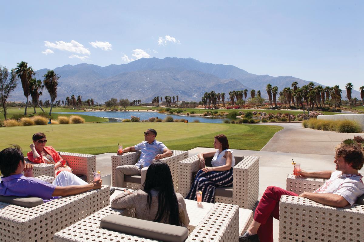 People meeting on a golf course with mountains in the background.
