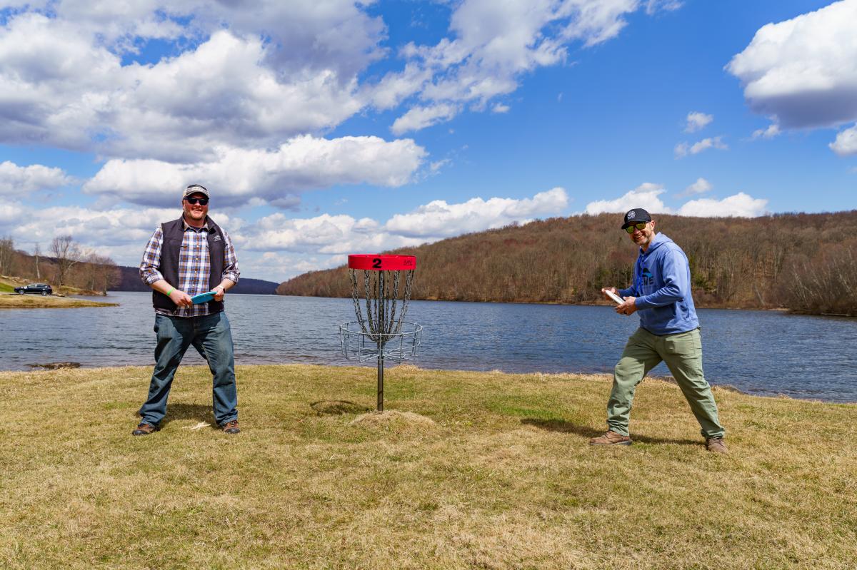 Jim and Dan pose by the disc golf basket