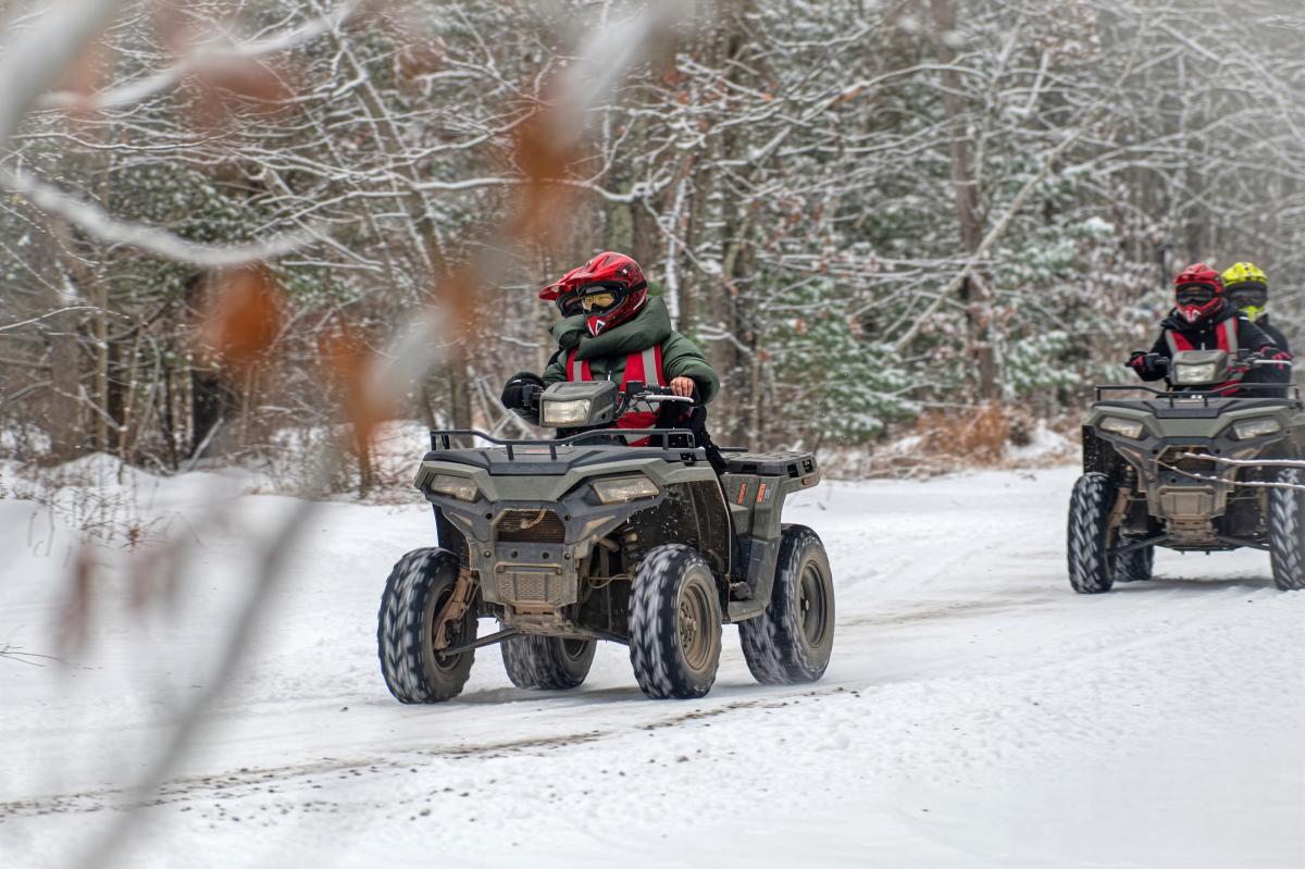 A group of riders enjoying an ATV tour on a snow-covered trail.