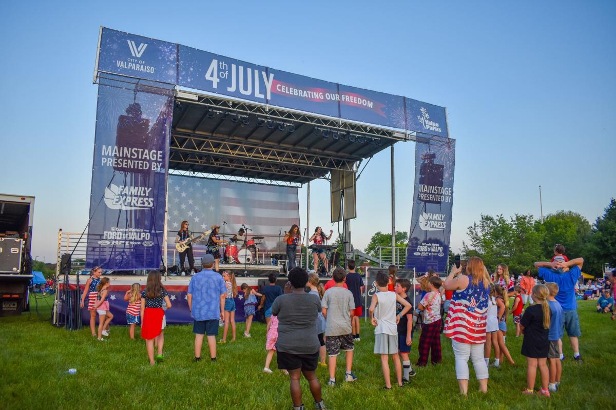 A crowd dressed in patriotic colors stands in front of a music stage