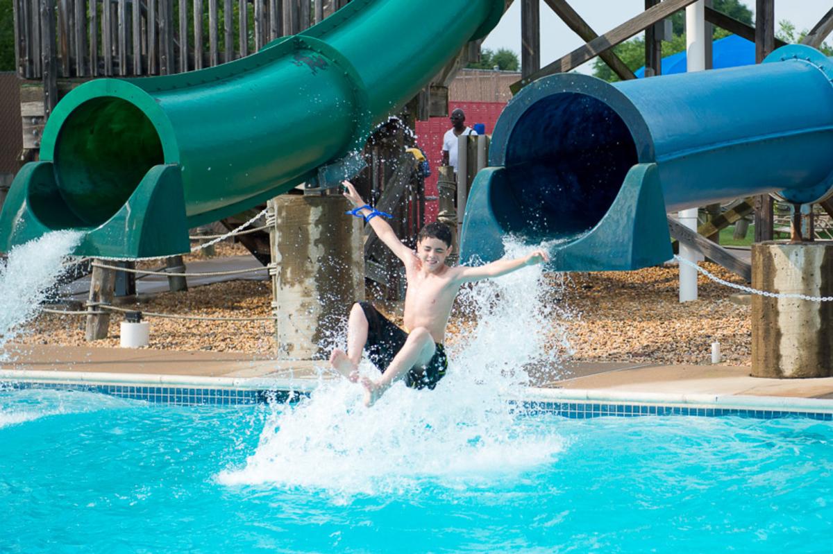2 waterslides, 1 has a boy mid-air on his way out of the waterslide before entering the water