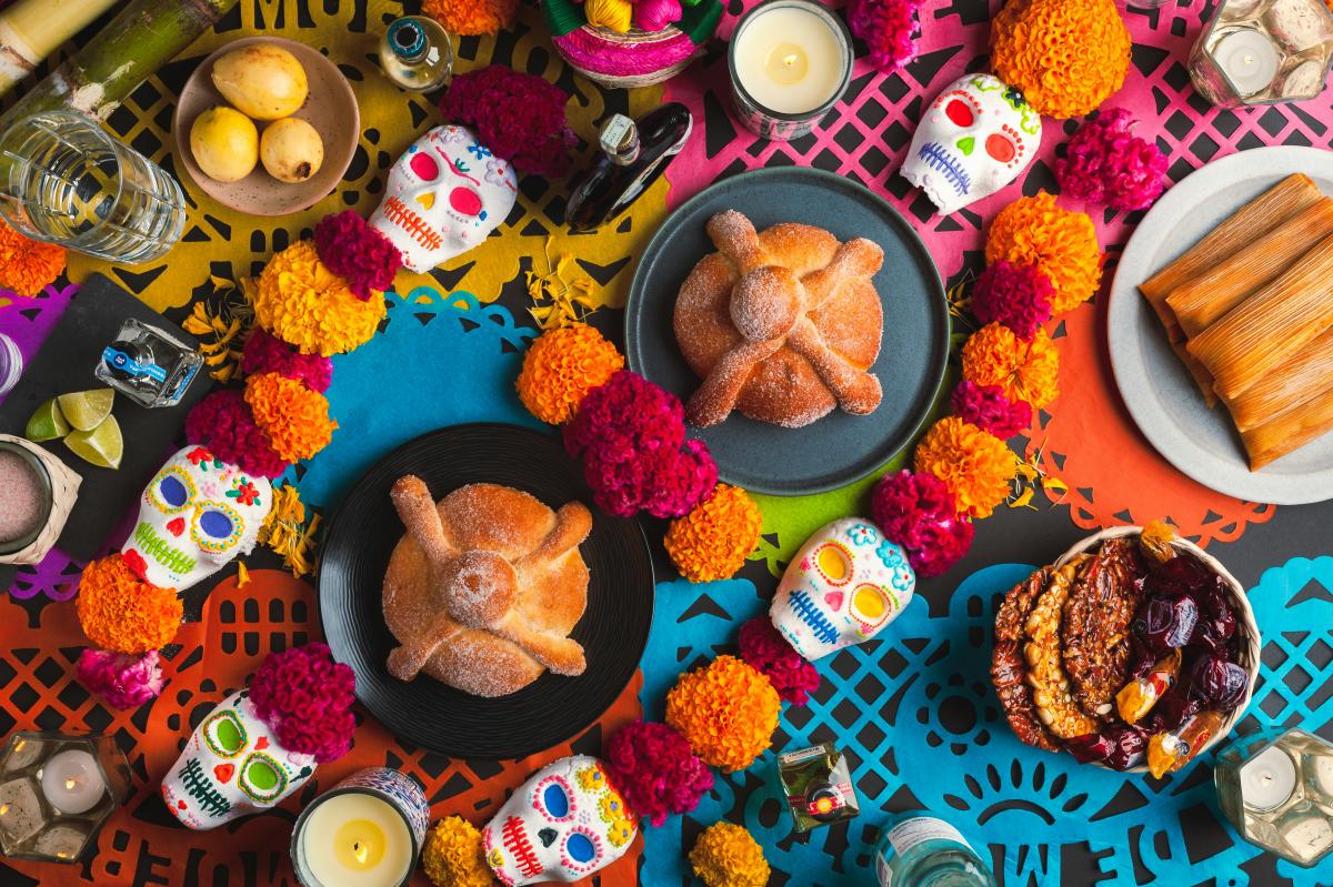 A colorful altar with sweet treats, marigolds, and candles