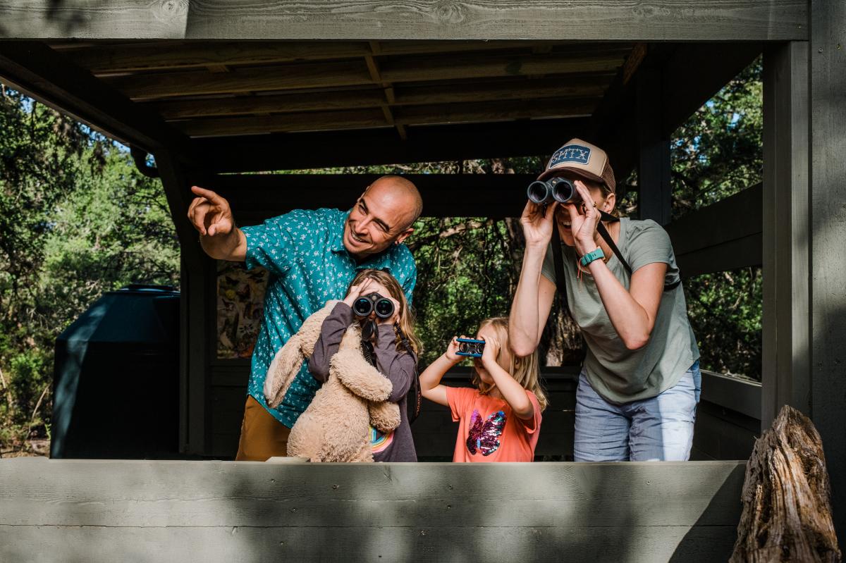 Family of four uses binoculars to find birds at Schulle Creek in San Marcos, Texas