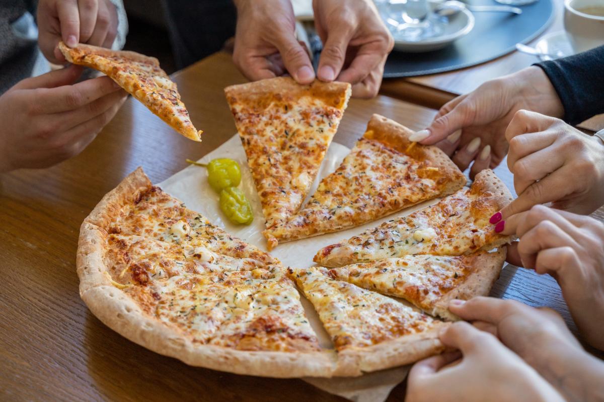 Group pulling pizza slices off tray