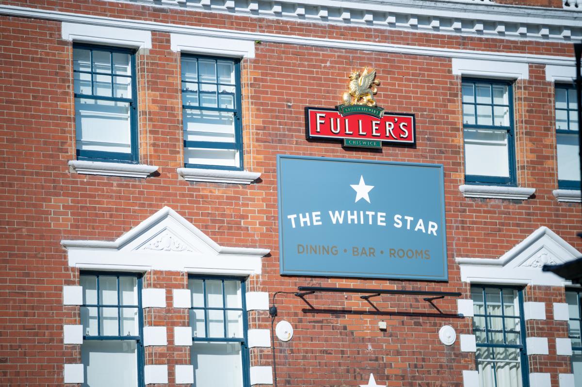 Top of the building showing The White Star Tavern sign on a brick wall.