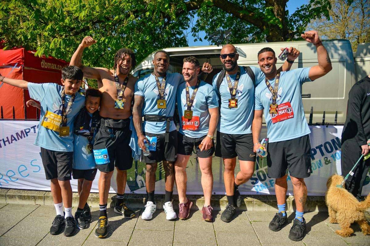 Group of young men and boys posing for photo with ABP Marathon medals around their necks