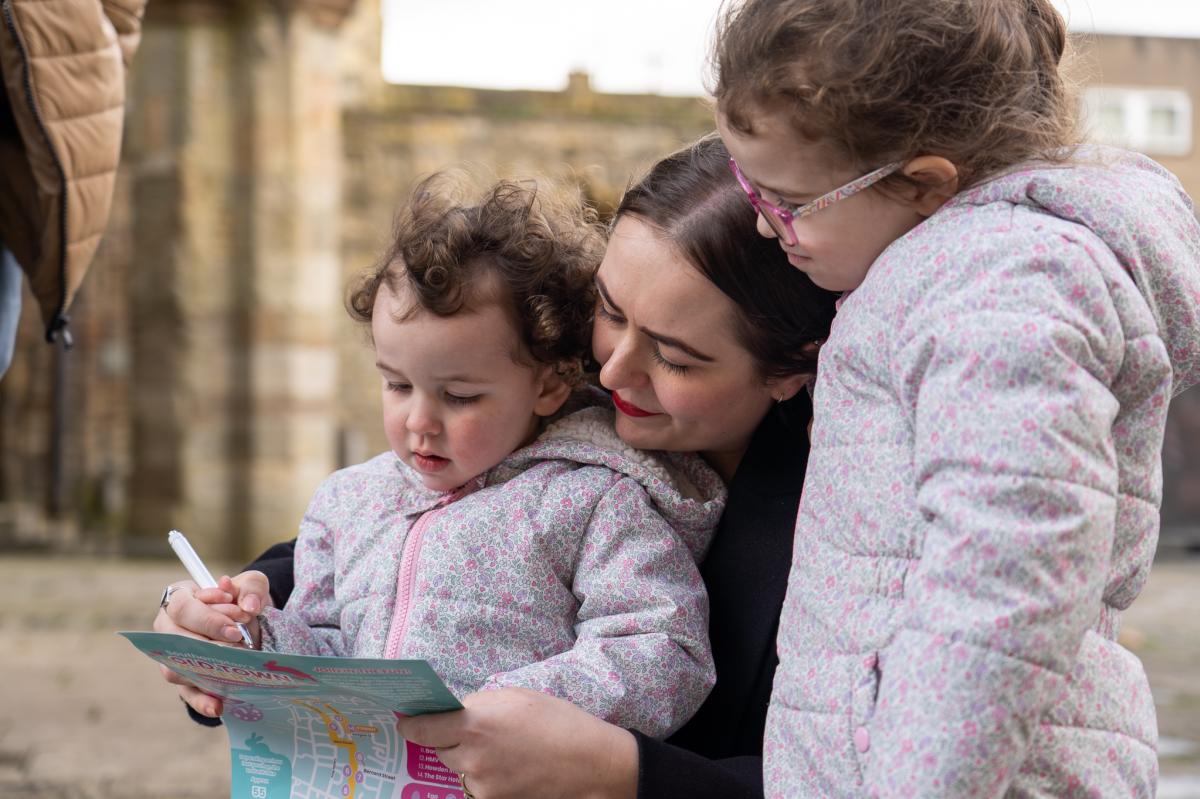 Mother helping two daughters write down clues on their Easter trail map