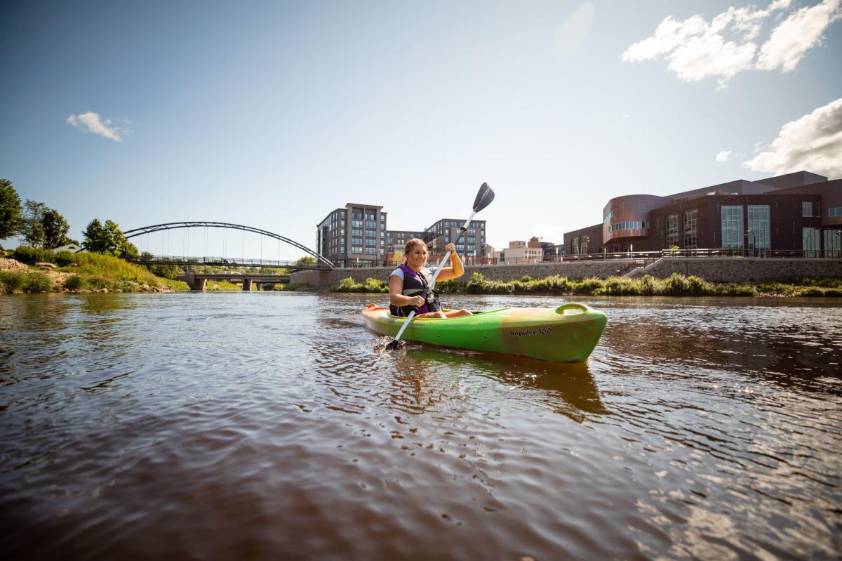 Kayaker on river near Pablo Center at the Confluence in downtown Eau Claire.