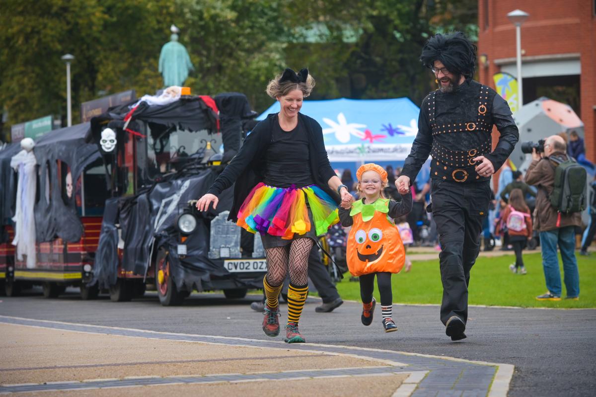 Family skipping alongside ghost train at halloween event