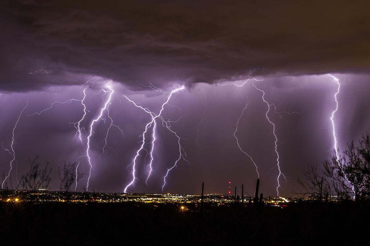 Cityscape of Tucson at night during a storm - several bolts of lightning in the sky