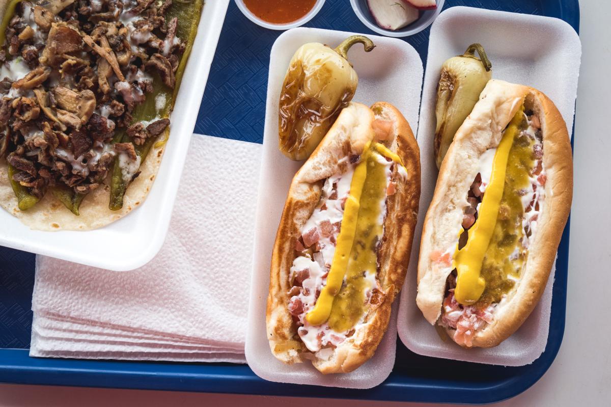 top down photos of two sonoran dogs with peppers on a blue tray