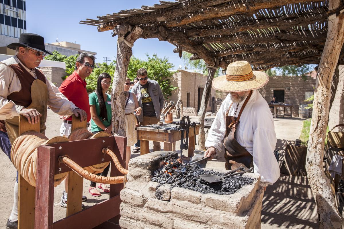 Man cooking on coals, reenacting presido living history day in front of several visitors