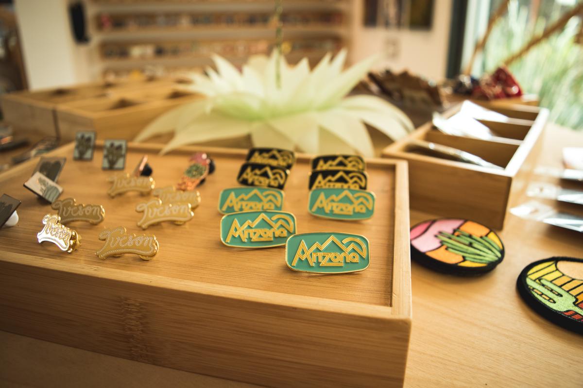 Close up of pins that say "Tucson" and "Arizona" on a store table