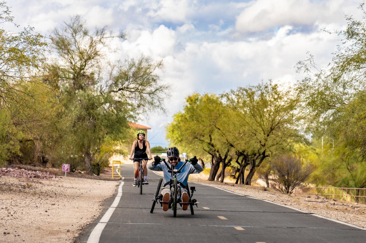 Man on a handbike and a woman on a bike cycling on a paved trail