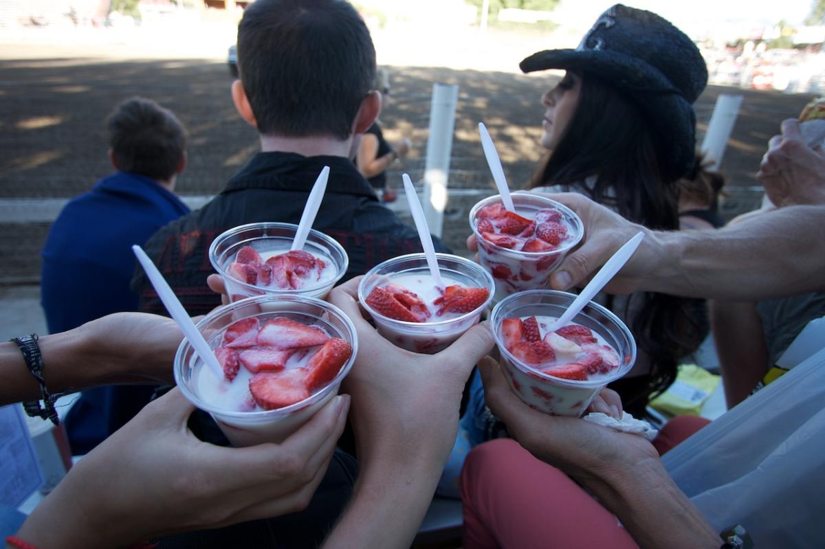 cups of strawberries and crème are held in hands