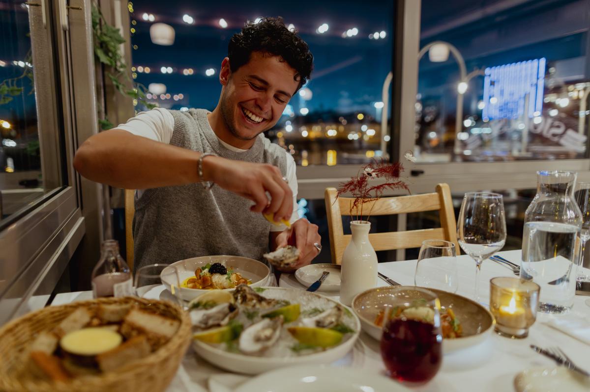 Mann spiser østers og smiler.