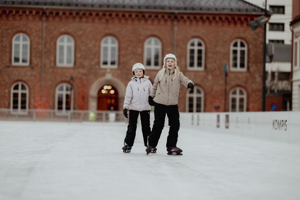 To jenter står på skøyter på Skøytebanen Kompis på Torvet i Kristiansand