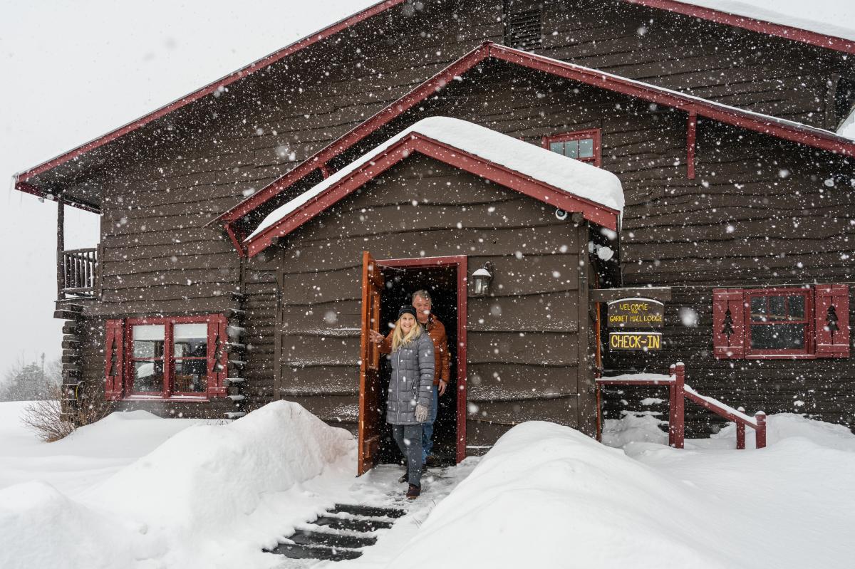 Couple walking out of Garnet Hill Lodge and into the snow